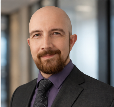 Headshot of man in a suit and tie in an office setting.