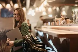 Smiling lawyer carrying a laptop away from a bar in a restaurant.